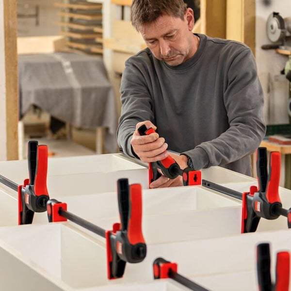 Ein Mann befestigt ein Werkstück mit einer Einhandzwinge