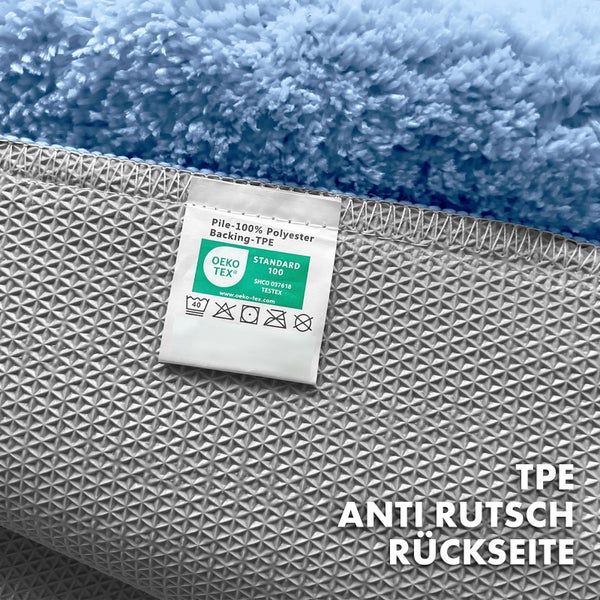 Detailansicht eines Teppichs mit Etikett, das die Materialzusammensetzung (100 % Polyester) und eine rutschfeste TPE-Rückseite angibt, sowie das OEKO-TEX Siegel.