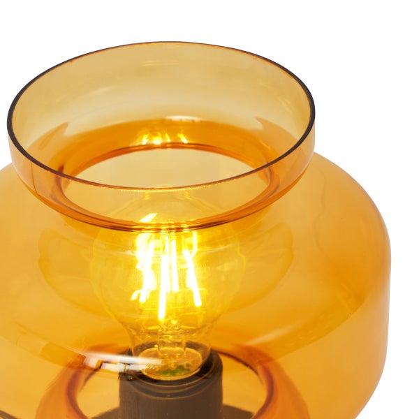 Tischleuchte mit bernsteinfarbenem Glasschirm und eingeschalteter Glühbirne