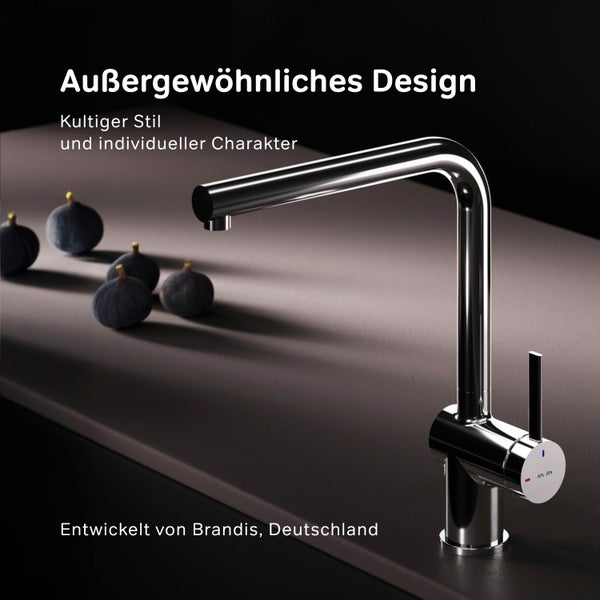 Moderner Wasserhahn aus Metall neben Früchten auf einer Arbeitsplatte