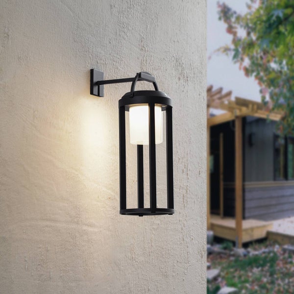 Moderne schwarze Außenwandleuchte in Laternenform mit weißem Leuchtenschirm, montiert an einer strukturierten Fassade.