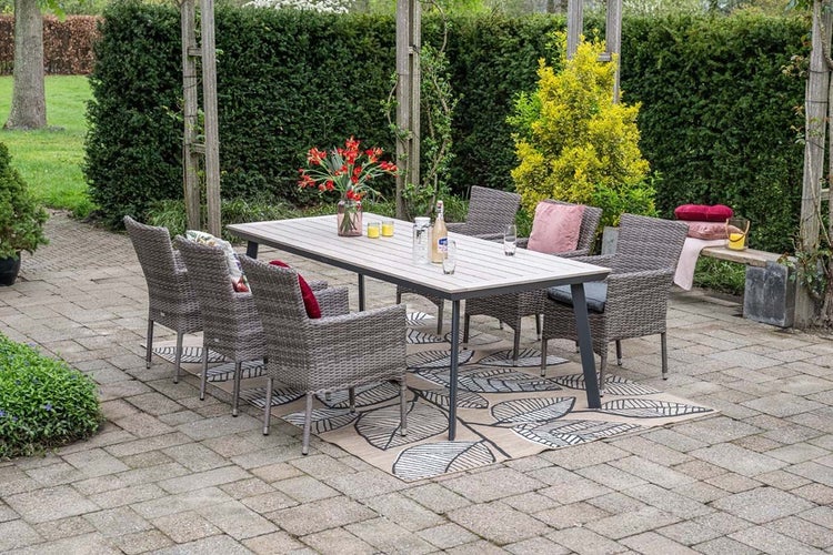 Garten-Essgruppe mit grauem Polyrattan-Geflecht, bestehend aus einem rechteckigen Tisch und sechs Stühlen auf einem gemusterten Teppich.