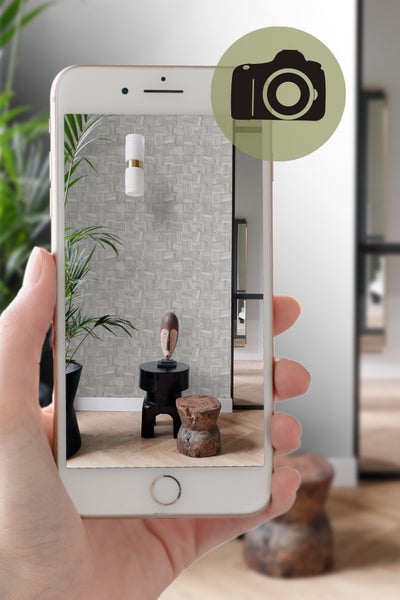 Aufnahme eines Raumes mit Mustertapete, Leuchte, Pflanze und Dekoration auf einem Smartphone