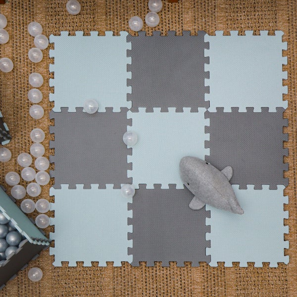 Puzzlematte als Bodenbelag für Kinderzimmer mit Spielzeugwal und Bällen auf strukturiertem Untergrund.