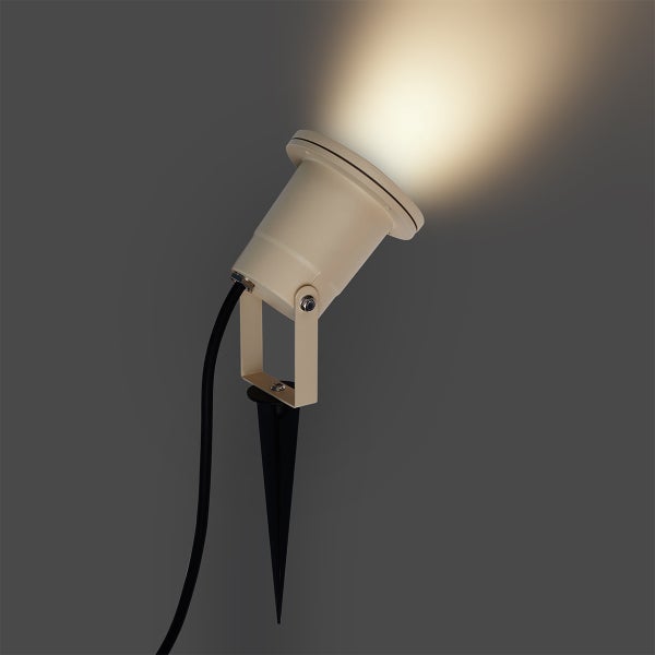 Beigefarbener LED-Gartenstrahler mit schwarzem Erdspieß und schwenkbarem Kopf inklusive Anschlusskabel.
