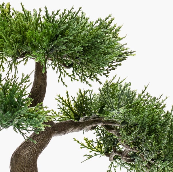 Nahaufnahme eines künstlichen Bonsai Baums mit strukturiertem braunem Stamm und grünen Nadelbüscheln