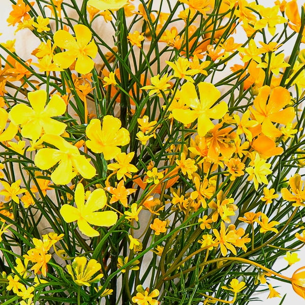 Künstliche gelbe Blüten an dünnen grünen Stielen zur Dekoration.