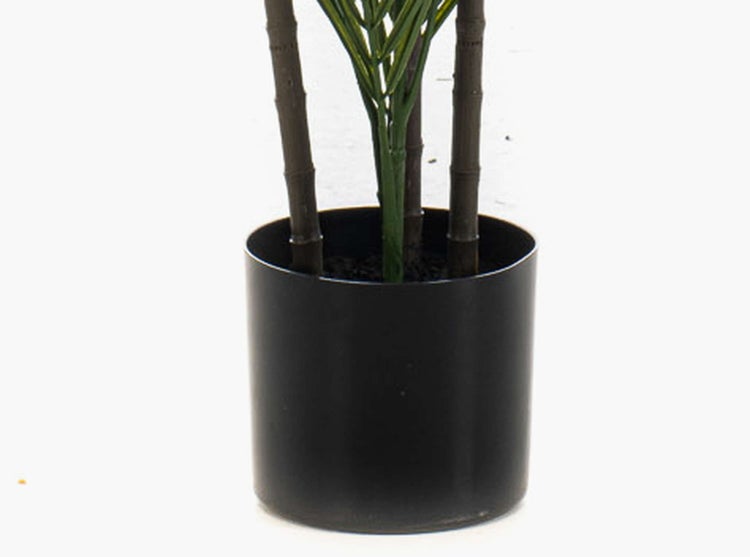 Künstliche Pflanze im schwarzen, zylindrischen Kunststofftopf mit Stämmen in Bambus-Optik.