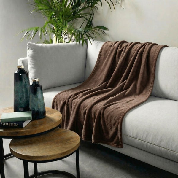 Wohnzimmer-Szene mit einem Sofa, einer braunen Fleecedecke und einem Beistelltisch aus Holz mit Dekorationsvasen.