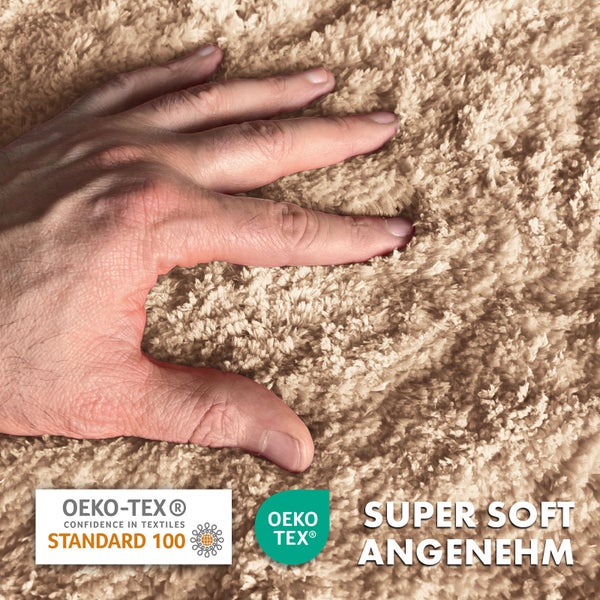 Nahaufnahme eines beigen Hochflorteppichs mit einer Hand, die die weiche Textur berührt. Mit den Siegeln Öko-Tex Standard 100 und Öko-Tex.