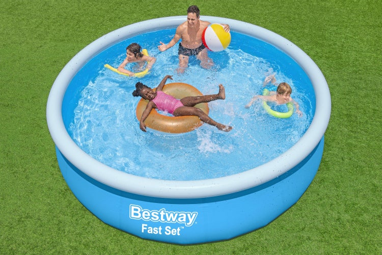 Runder blauer Bestway Fast Set Aufstellpool mit aufblasbarem Ring auf einer Rasenfläche. Ein Mann und drei Kinder spielen mit Wasserball und Reifen.