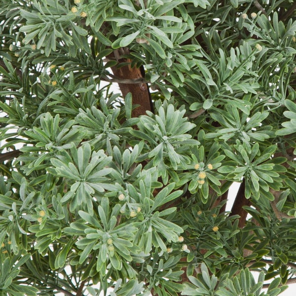 Detailaufnahme einer künstlichen Pflanze mit grünen Blättern und kleinen hellen Knospen.