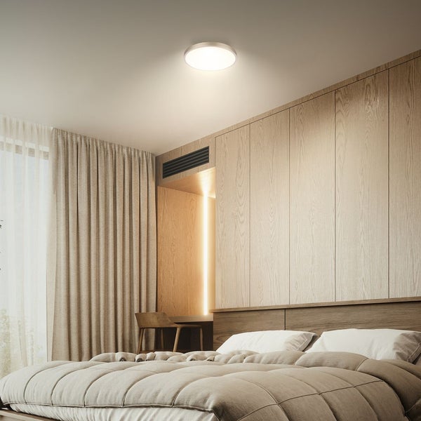 Moderne LED Deckenleuchte in einem Schlafzimmer mit Holzoptik Paneelen und beigefarbenen Textilien für eine wohnliche Atmosphäre.