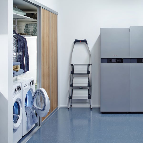 Wäscheraum mit Waschmaschinen, Wäsche, Schrank mit Schiebetüren, Trittleiter und Heizungsanlage