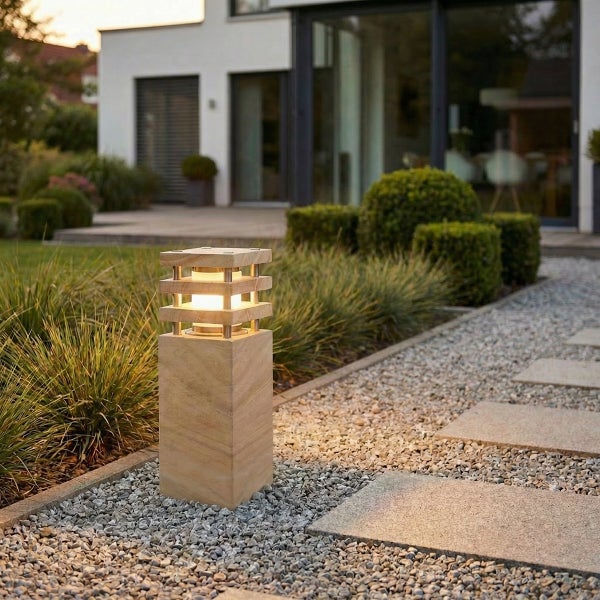 Moderne quadratische Außenleuchte aus Naturstein im Gartenweg mit integrierter LED Beleuchtung vor einem modernen Wohnhaus.