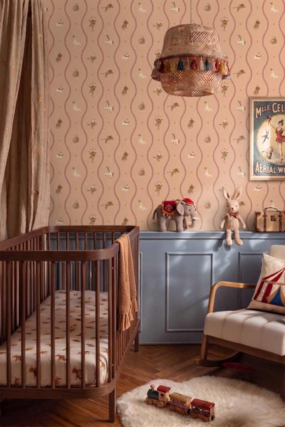 Kinderzimmer im Zirkus-Stil mit gemusterter Tapete, Gitterbett aus Holz, Wandpaneelen, geflochtener Pendelleuchte und Spielzeug.