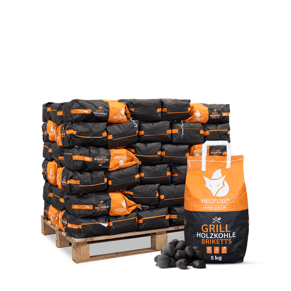 Heizfuxx Grill Holzkohle Briketts, 5 Kilogramm Beutel auf Holzpalette gestapelt, mit einem Beutel und losen Briketts davor.