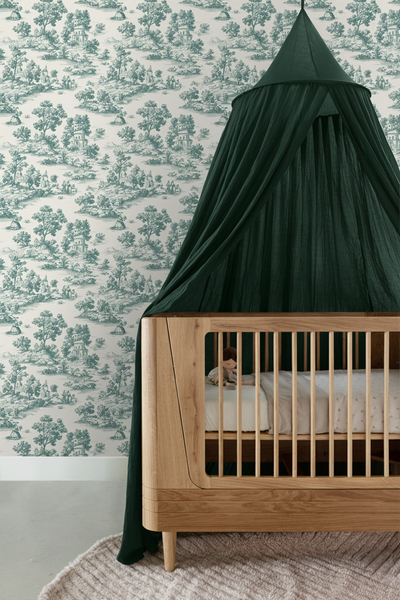 Helles Kinderzimmer mit Vliestapete im Toile-de-Jouy-Stil, hölzernem Gitterbett und dunkelgrünem Betthimmel.