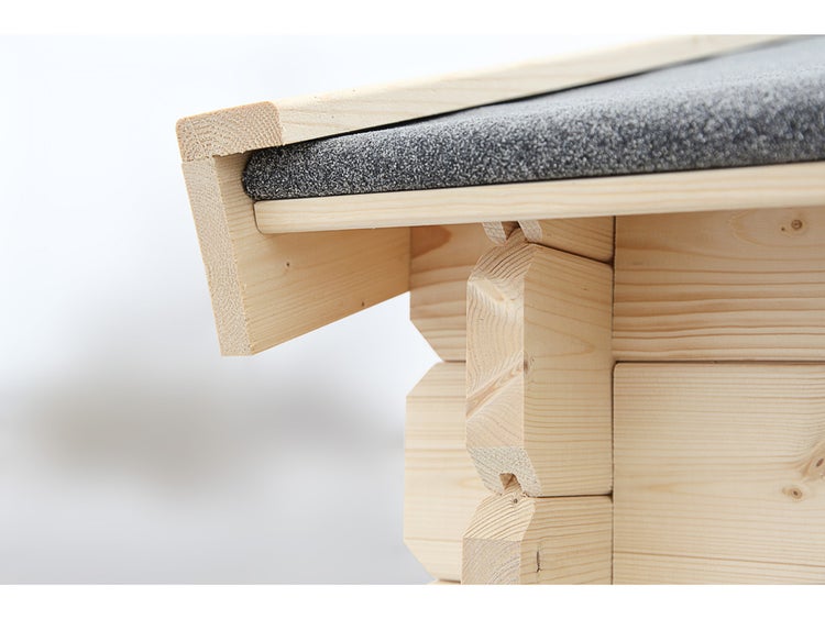 Detailaufnahme der Eckverbindung und Dachkante eines Gartenhauses aus hellem Holz mit Bitumendachpappe.