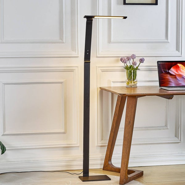 Moderne schwarze LED-Stehleuchte in einem hellen, organisierten Arbeitszimmer mit Holztisch und Wandtäfelung.