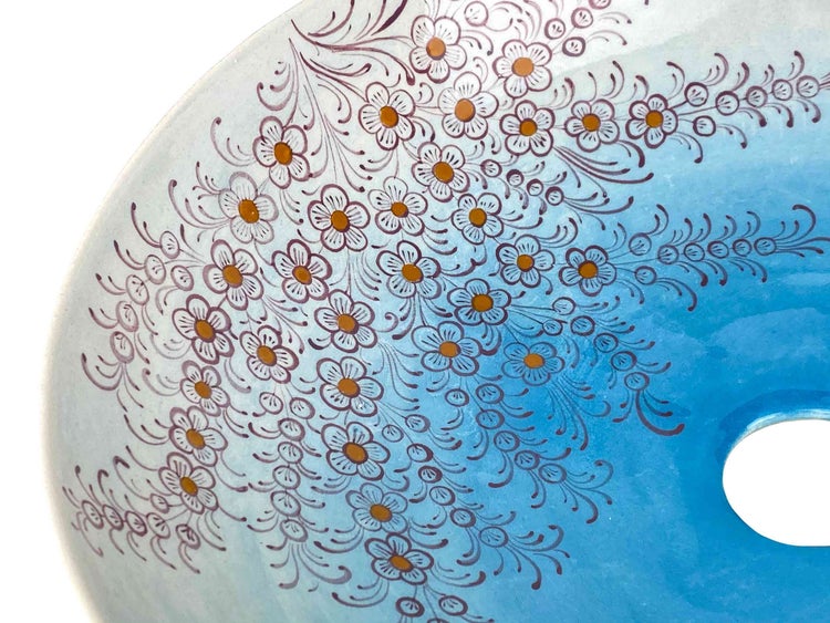 Detailansicht eines blauen Keramikwaschbeckens mit floralem Muster