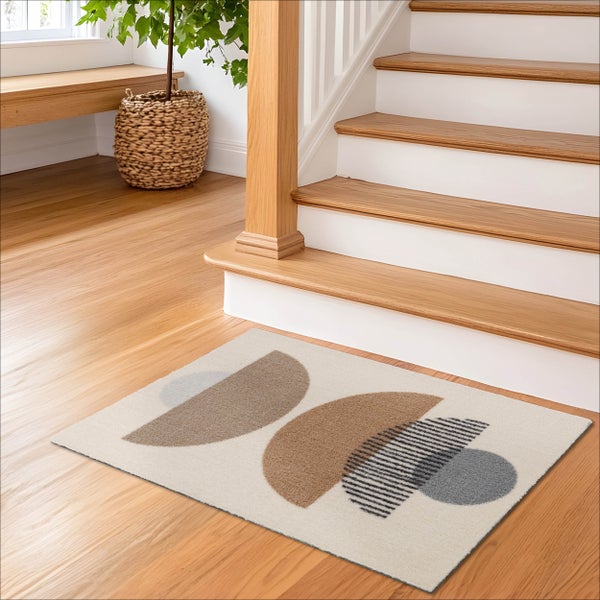 Moderner Teppich mit geometrischen Mustern vor einer Holztreppe in einem hellen Flur.