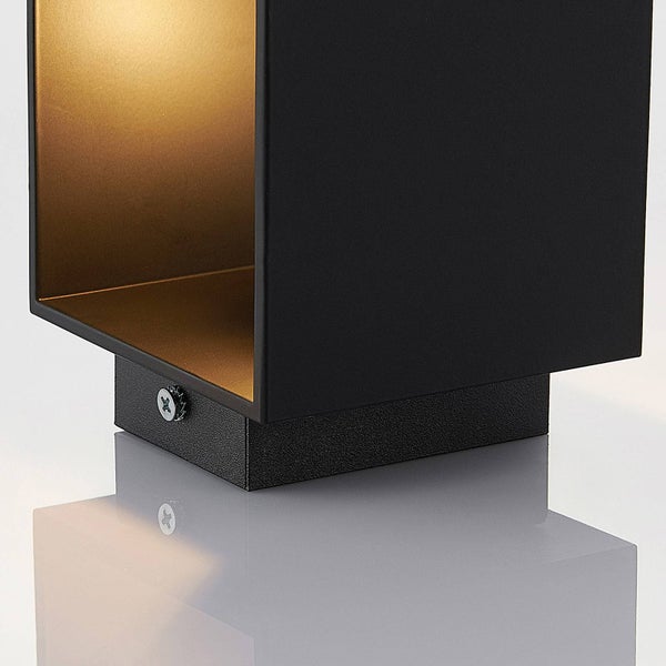 Detailansicht einer quadratischen Leuchte in Schwarz mit goldener Innenseite und warmem Lichtschein.