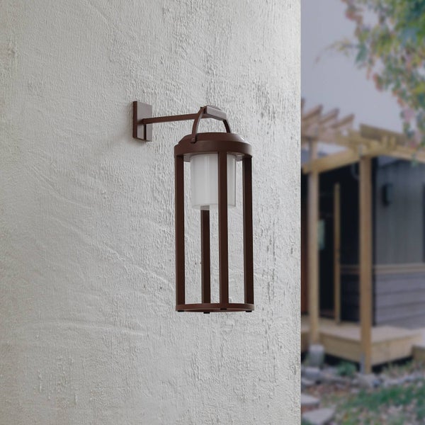 Moderne Wandaußenleuchte in Laternenform mit braunem Metallrahmen und weißem Diffusor an einer strukturierten Wand.