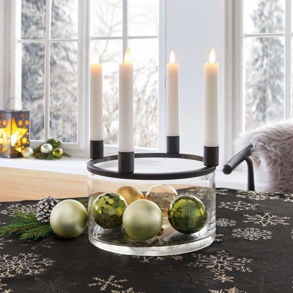 Adventskranz mit vier Kerzen in einem Glasgefäß, dekoriert mit Weihnachtskugeln.