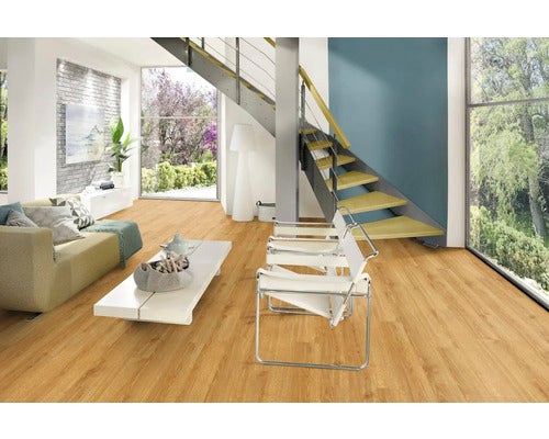 Hell gestalteter Wohnraum mit Laminatboden in Holzoptik, moderner Couch, Designerstühlen und einer offenen Treppe.