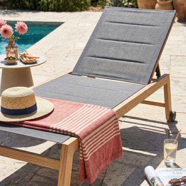 Moderne Gartenliege aus Holz und Textil mit verstellbarer Rückenlehne und Rollen in einem hellen Außenbereich am Pool.
