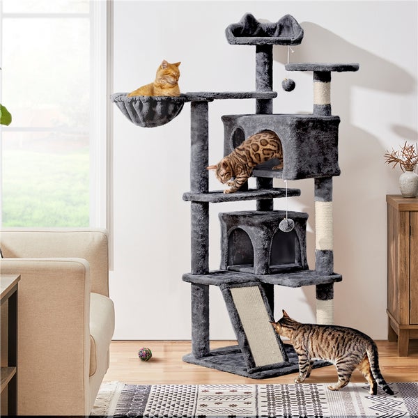 Mehrstöckiger Katzenbaum mit Kratzbaum, Liegeflächen und Katzenhäusern in einem Wohnzimmer mit drei Katzen
