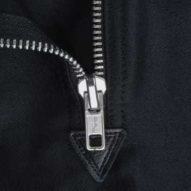 Nahaufnahme eines Metallreißverschlusses an einem dunklen Kleidungsstück mit JOB Logo auf dem Schieber.