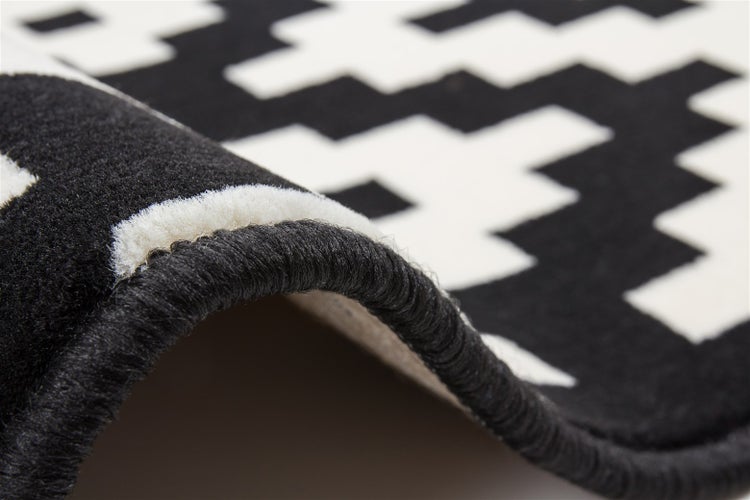 Detailansicht eines Teppichs mit geometrischem Muster und gekettelter Kante