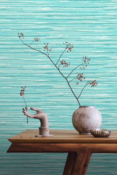 Dekoratives Interieur mit einer Vase, einer Handskulptur und einem Zweig mit Beeren vor einer strukturierten Tapete