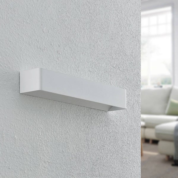 Moderne, rechteckige Wandleuchte aus Metall an einer strukturierten Wand in einem hellen Wohnraum.