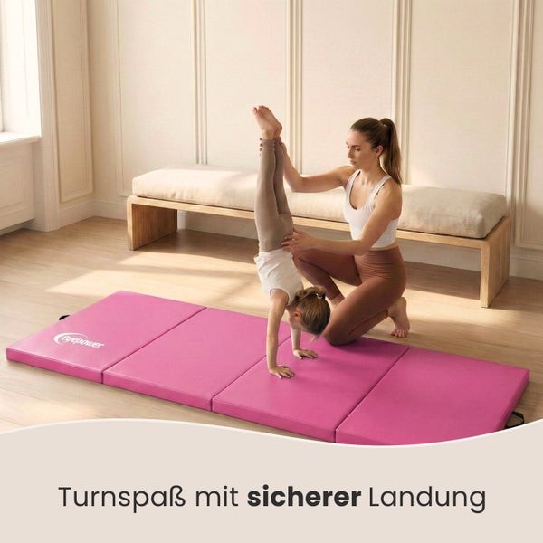 Mädchen macht Handstand auf einer faltbaren Turnmatte mit Mutter zur Unterstützung