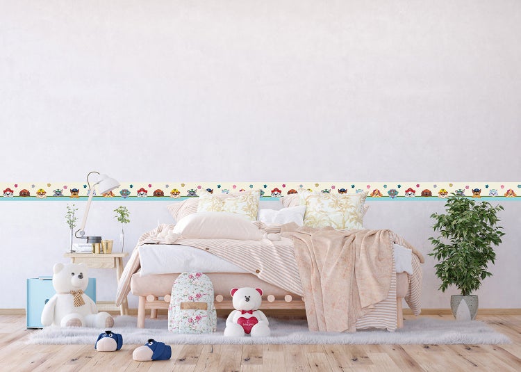 Wandborte mit Paw Patrol Motiven in einem hellen Kinderzimmer horizontal an der Wand über einem Bett angebracht.