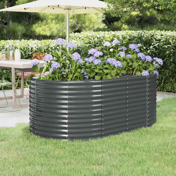 Ovales Hochbeet aus Metall mit Wellenstruktur, bepflanzt mit Blumen auf einer Rasenfläche im Garten.