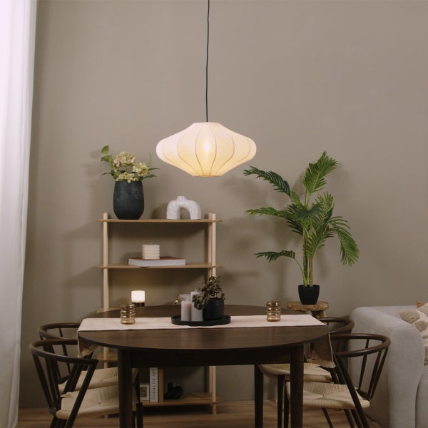 Moderner Essbereich mit rundem Holztisch, Stühlen mit Geflechtsitz, einem hellen Holzregal und einer großen Zimmerpflanze sowie weißer Pendelleuchte.