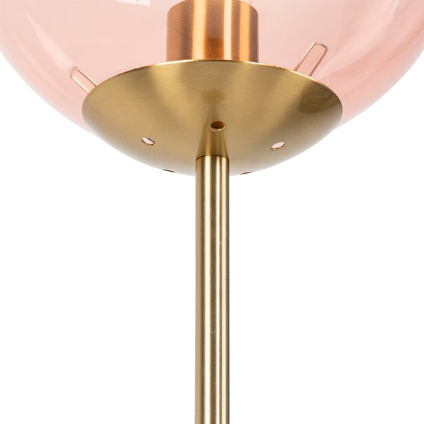 Detailaufnahme einer Stehlampe mit rosafarbenem Glasschirm und goldfarbenem Metallfuß.