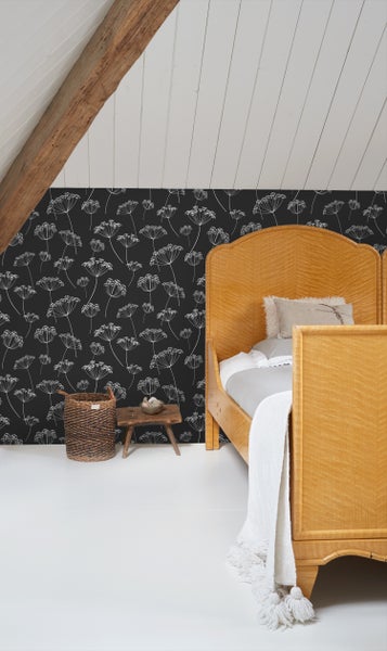 Schlafzimmer mit gemusterten Tapeten, Bett aus Holz, Beistelltisch und Weidenkorb