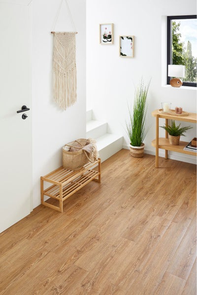 Helle Diele mit Laminatboden in Holzoptik, weißer Wand, Treppe, Holzschuhregal und dekorativem Makramee-Wandschmuck.