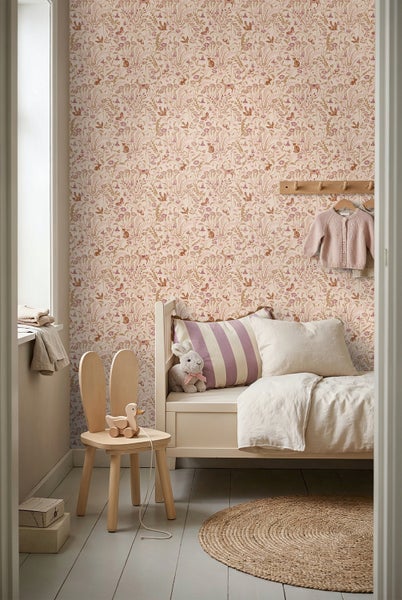 Hell eingerichtetes Kinderzimmer mit Tapete mit Tier- und Blumenmuster, Holzbett, Holzkinderstuhl mit Hasenohren und rundem Juteteppich.