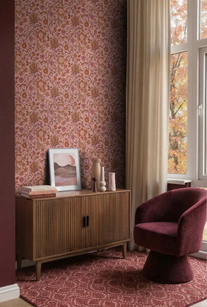 Vliestapete mit Blumenmuster an einer Wand hinter einer Holzkommode, einem Samtsessel und einem gemusterten Teppich.