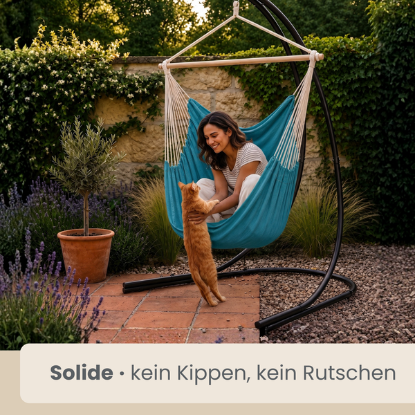 Frau sitzt entspannt in einem Hängesessel mit Gestell im Garten und spielt mit einer Katze. Der Hängesessel bietet stabilen Halt.
