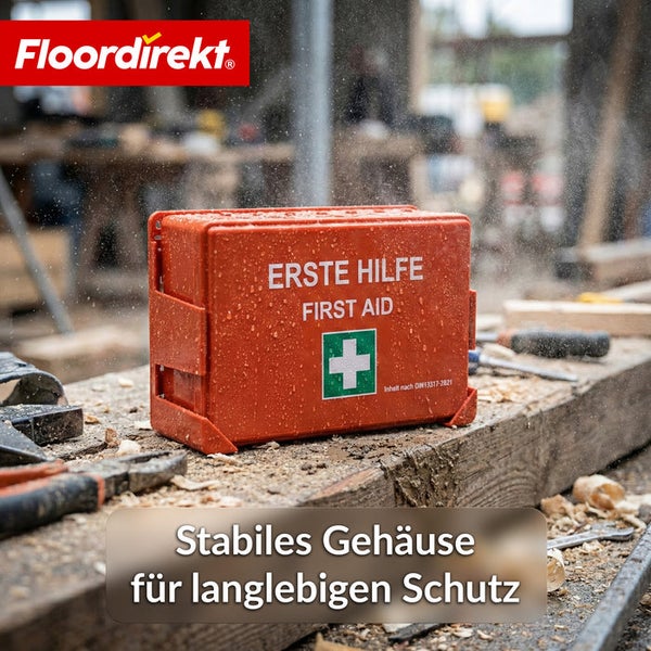 Floordirekt Logo. Robuster Verbandkasten auf einem Holzbalken in einer Werkstatt mit Werkzeugen und Holzspänen.