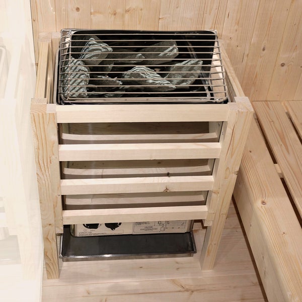 Saunaofen mit Saunasteinen hinter einem hölzernen Schutzgitter in einer Sauna mit Holzwand und Sitzbank.