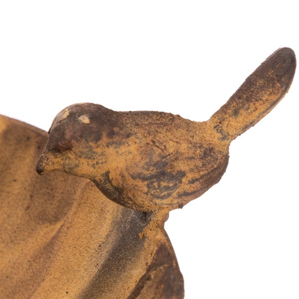 Dekorative Vogelfigur aus Gusseisen in Rostoptik auf einer Gartenschale.