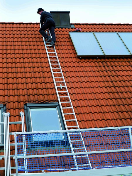 Mann auf Leiter auf einem Dach mit Dachfenster und Solaranlage.